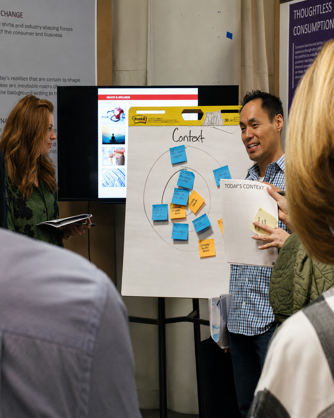 Andrew facilitating a Context mapping session with a group of leaders gathered around a flip chart covered in sticky notes.
